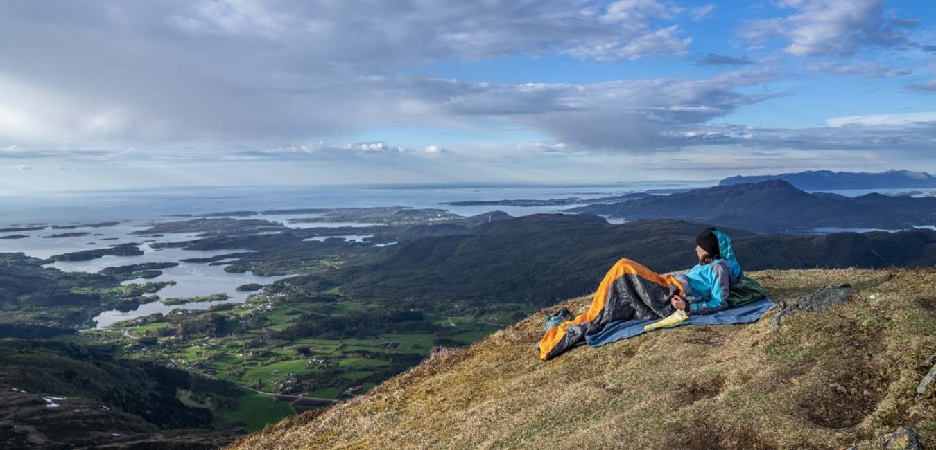 En person nyter fjordutsikt fra en fjelltopp. Foto. 